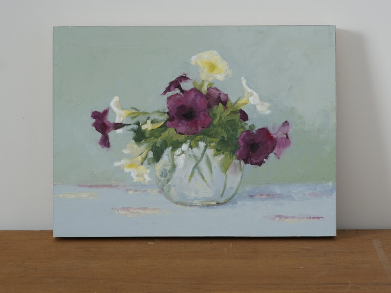 Still life oil painting of pale yellow and red-violet petunias in a clear, rounded vase with a blue and green background. Nicole Lamothe artwork
